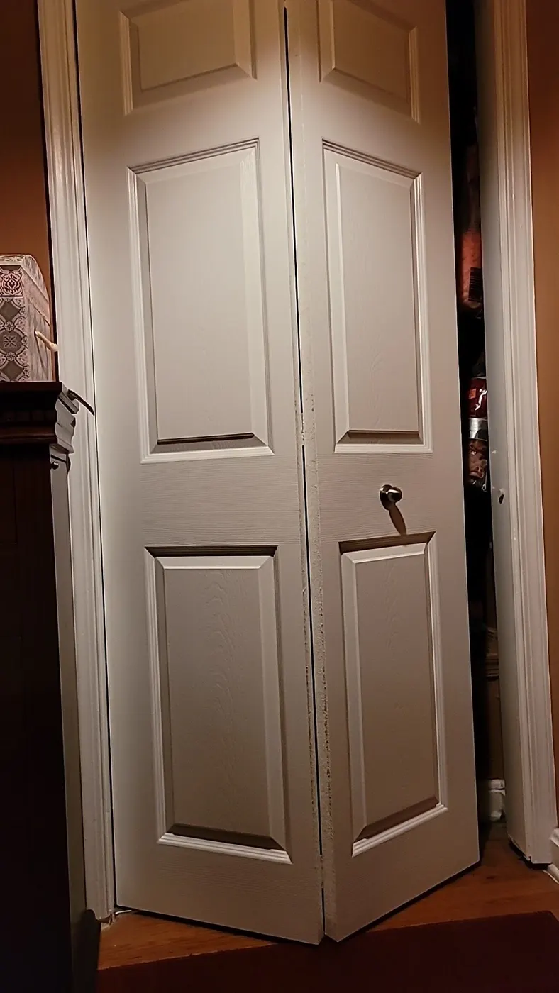White six-panel bifold closet doors with dark knobs