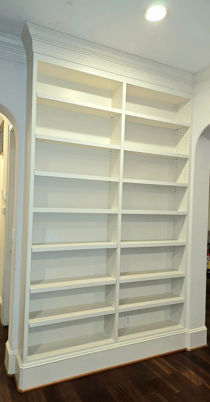 Floor-to-ceiling built-in bookshelves painted white, with crown molding across the top
