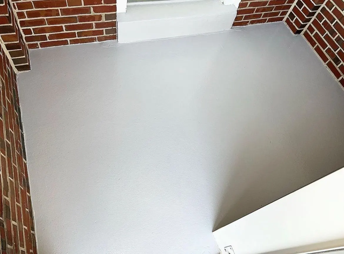 The same entry floor after coating, a clean smooth light gray between the red brick walls