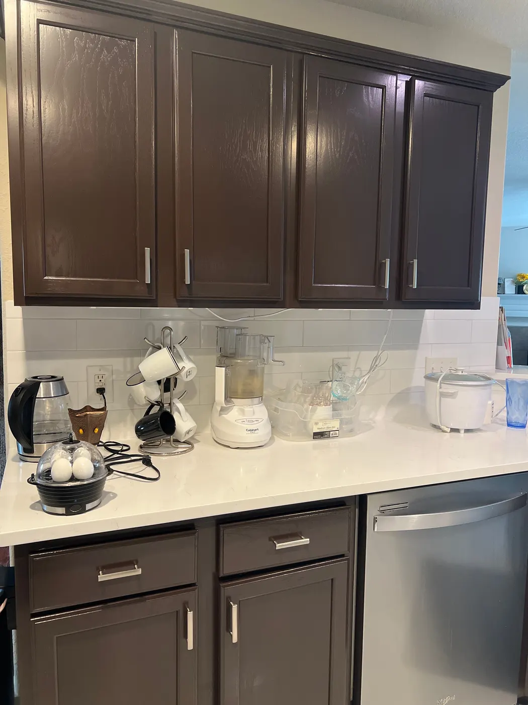 Kitchen upper and lower cabinets in dark espresso brown around a white quartz counter with a coffee station