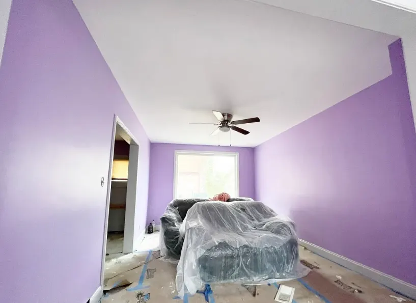 Bedroom walls painted lavender, the furniture wrapped in plastic and the floor covered while the work is under way