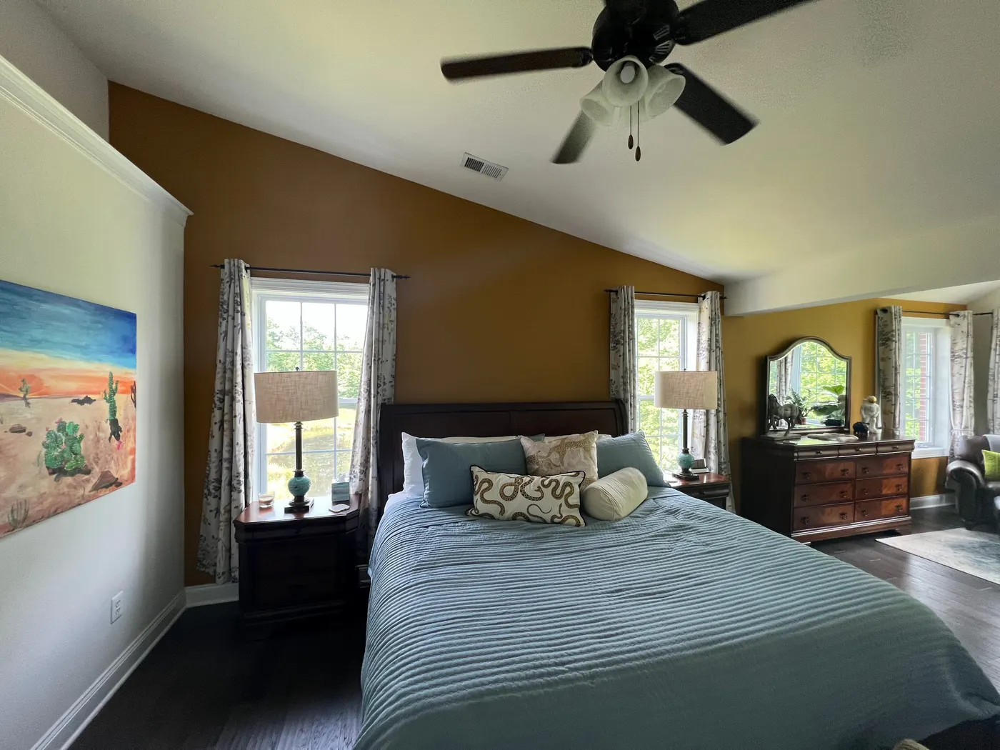 Bedroom with a mustard yellow accent wall under a vaulted ceiling, the other walls white