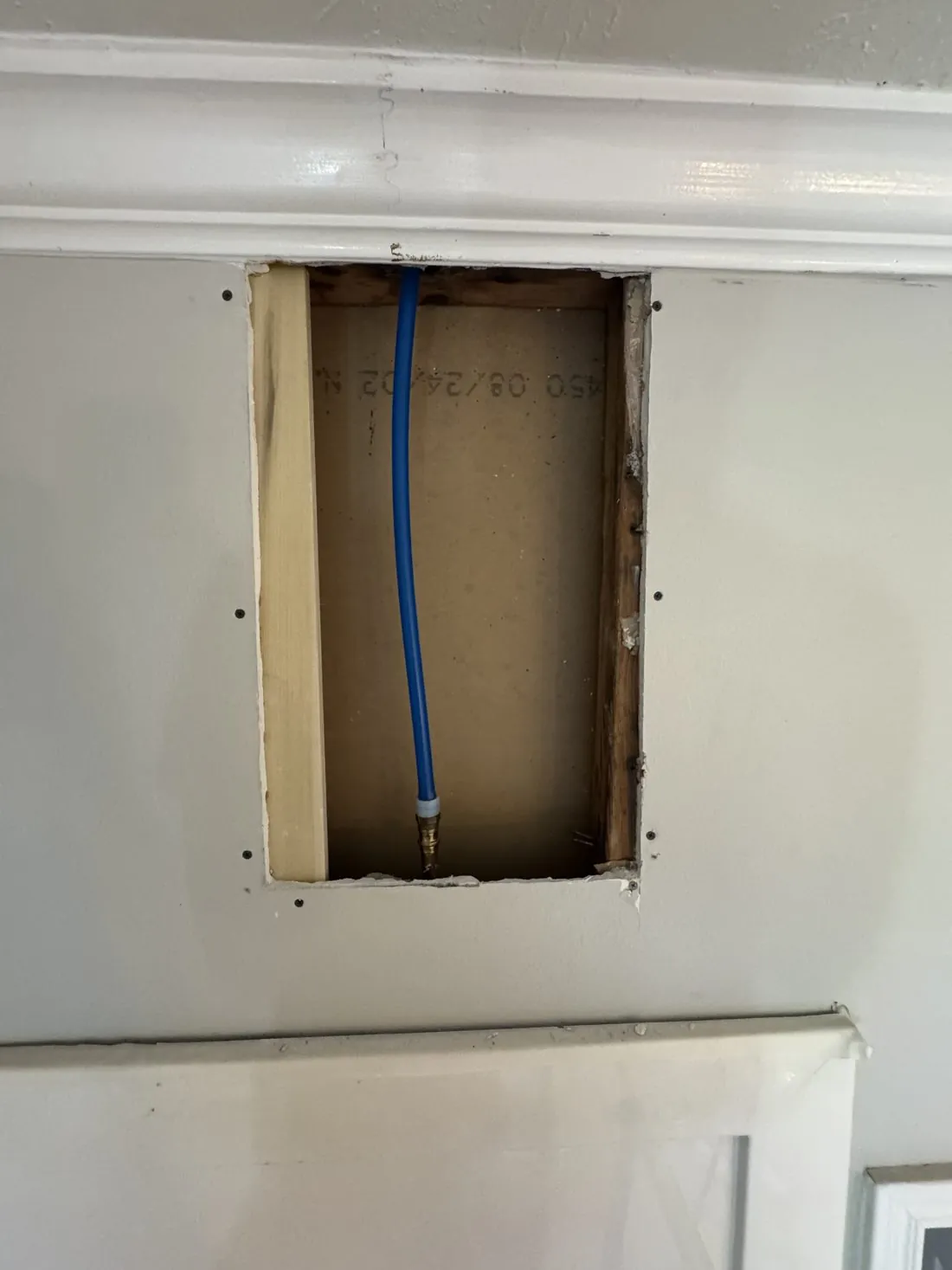The same wall opening with timber backing screwed into place around the edges, ready to take a patch