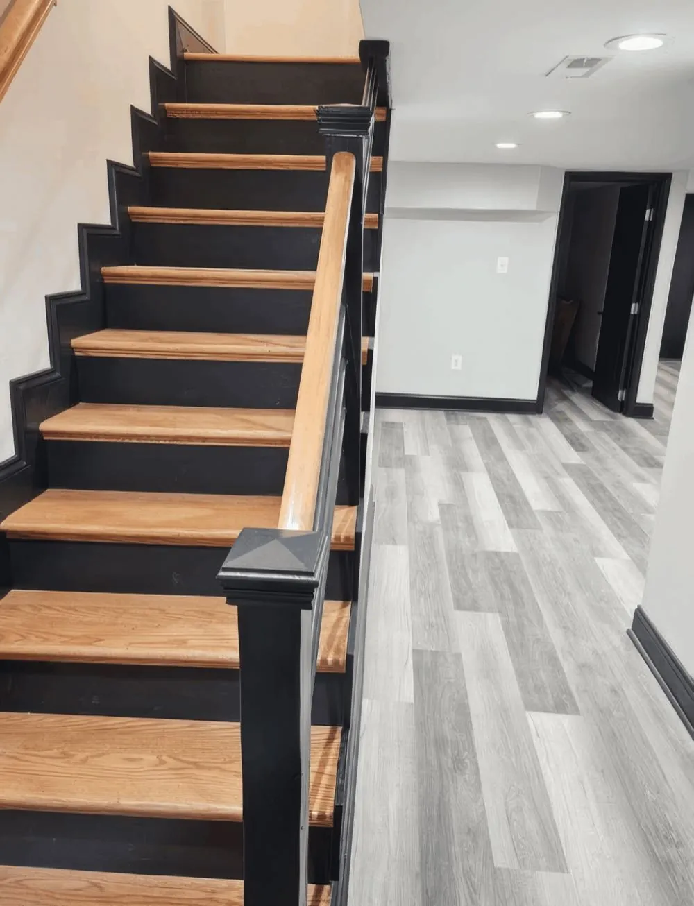 Staircase repainted by Rise and Prime Painting with black risers, stringer and newel post against natural oak treads